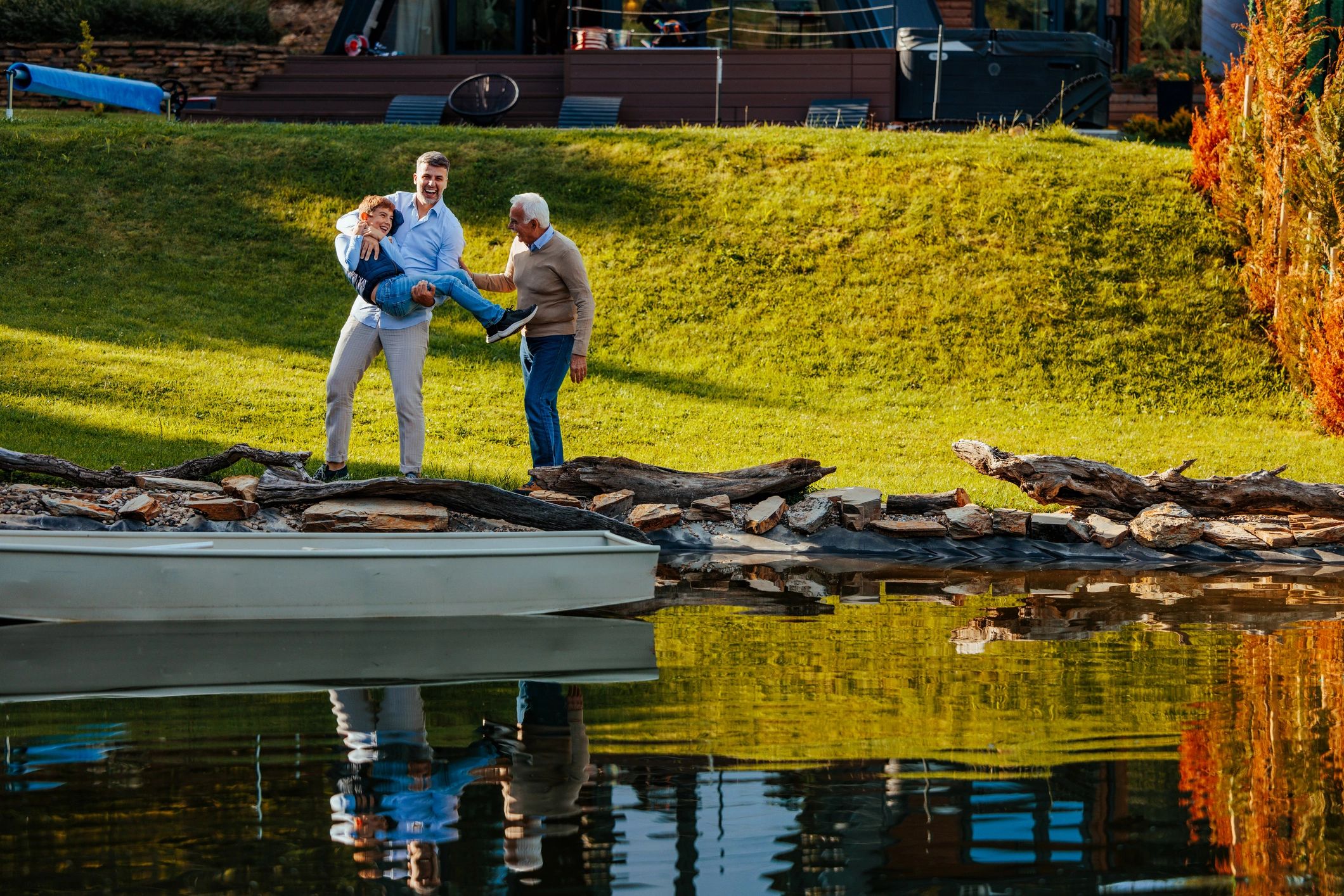 Family by a pond with a small boat, reflecting community and tradition